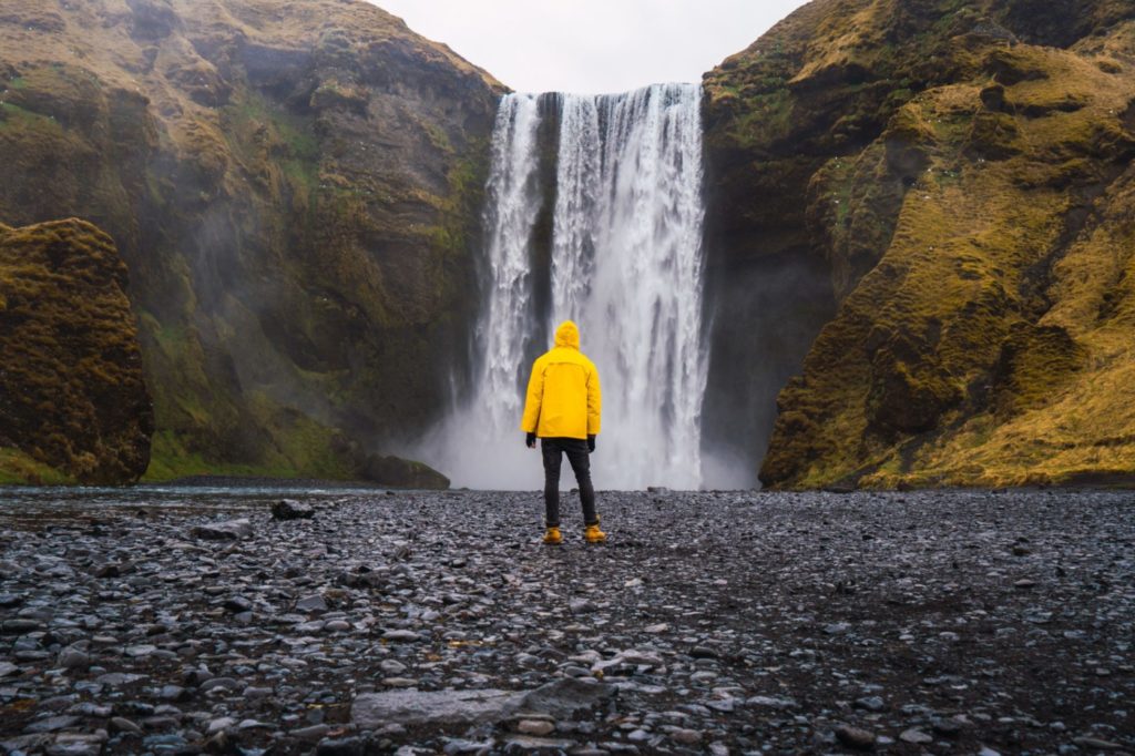 Man standing near waterfall