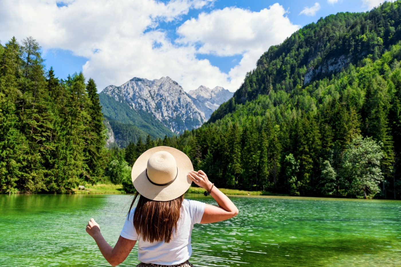Rear view of woman standing by idyllic lake in mountains.
