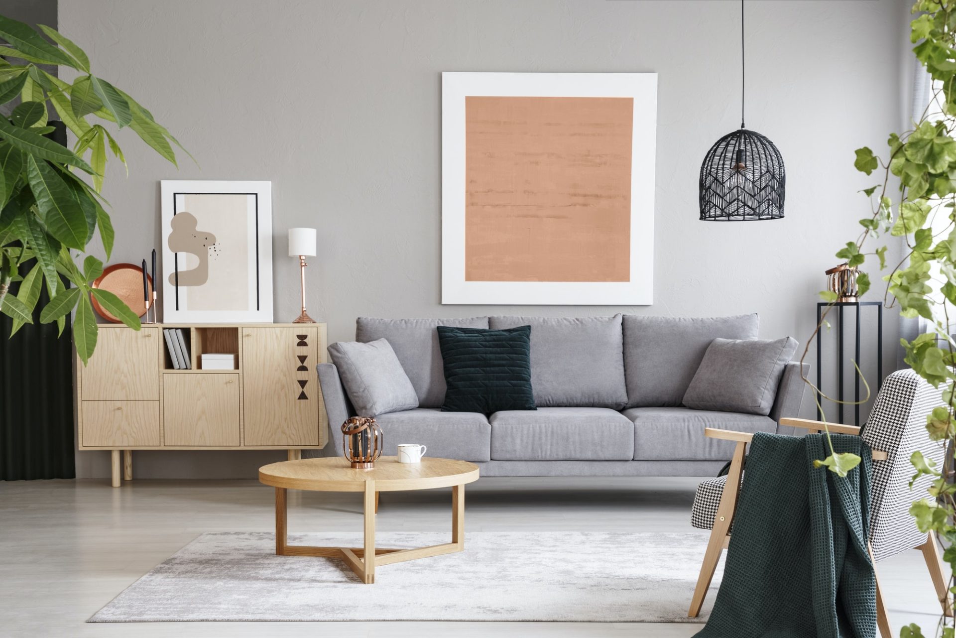 Pink poster above grey sofa in living room interior with wooden