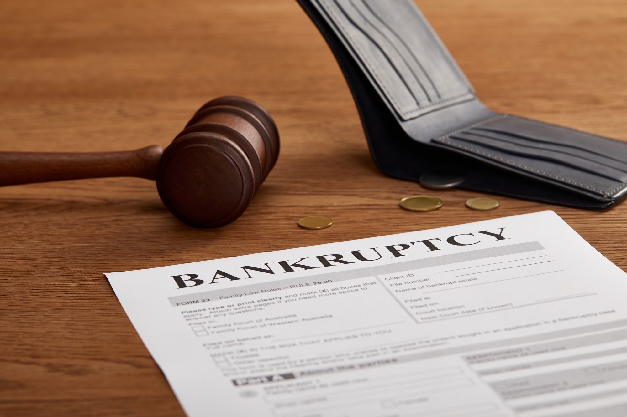 bankruptcy form with wooden gavel, coins and wallet on brown wooden table