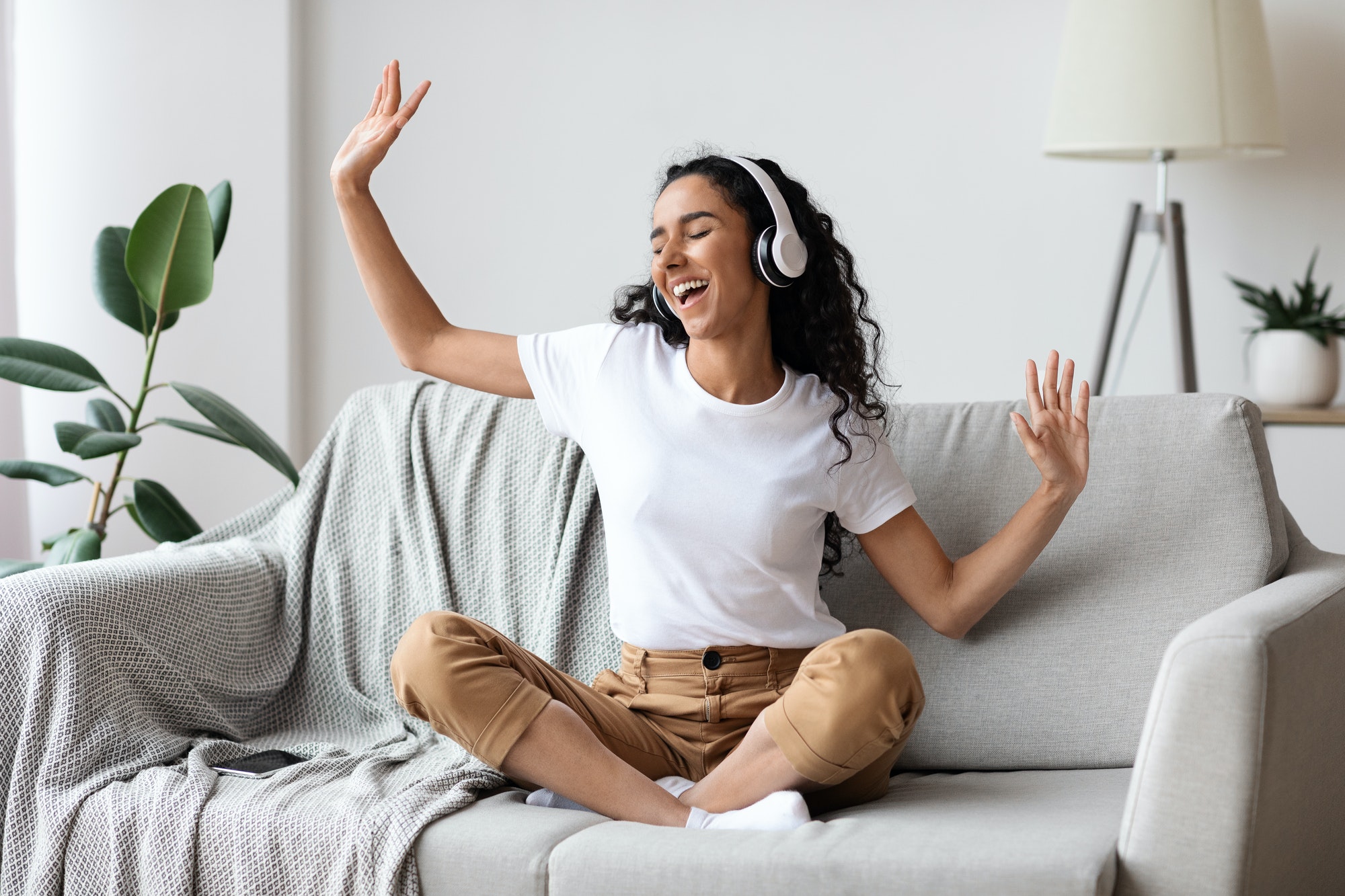 Carefree woman listening to music and singing, using headphones