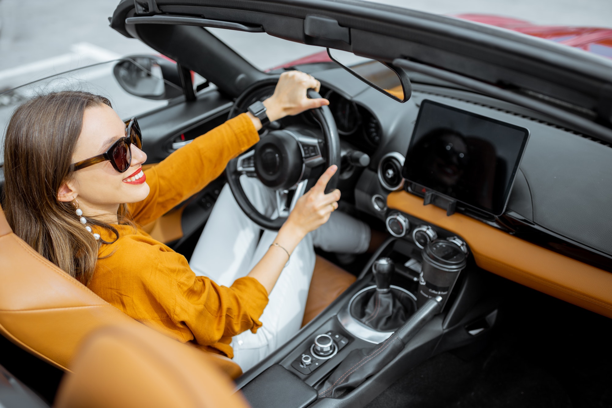 Woman driving sports car with a digital touchscreen