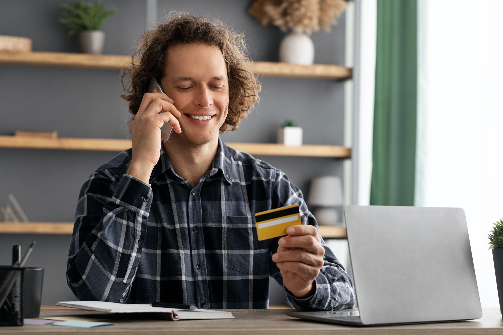 Cheerful Man Holding Credit Card Calling To Bank In Office