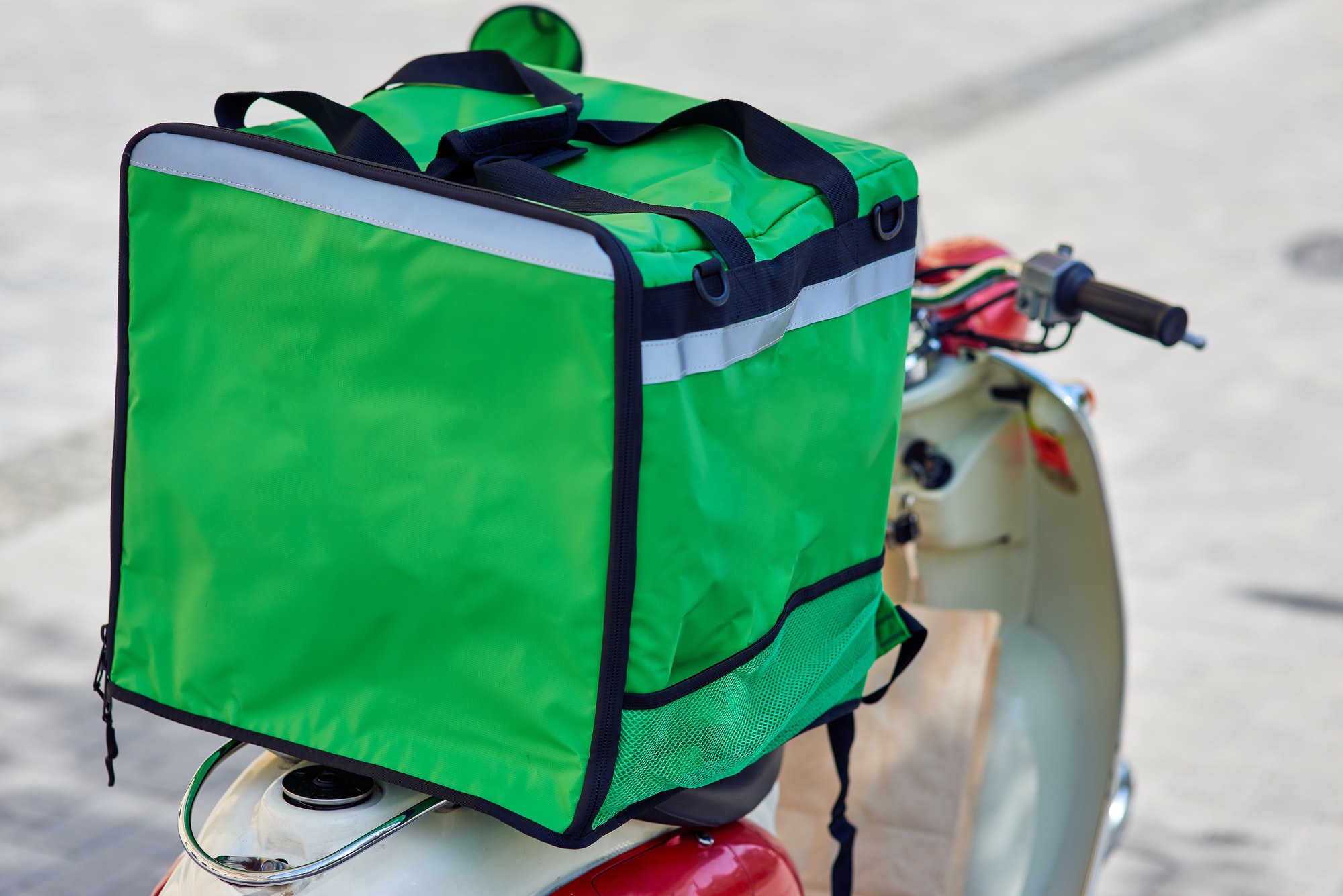 Green thermo backpack with food and drinks on scooter standing outdoors