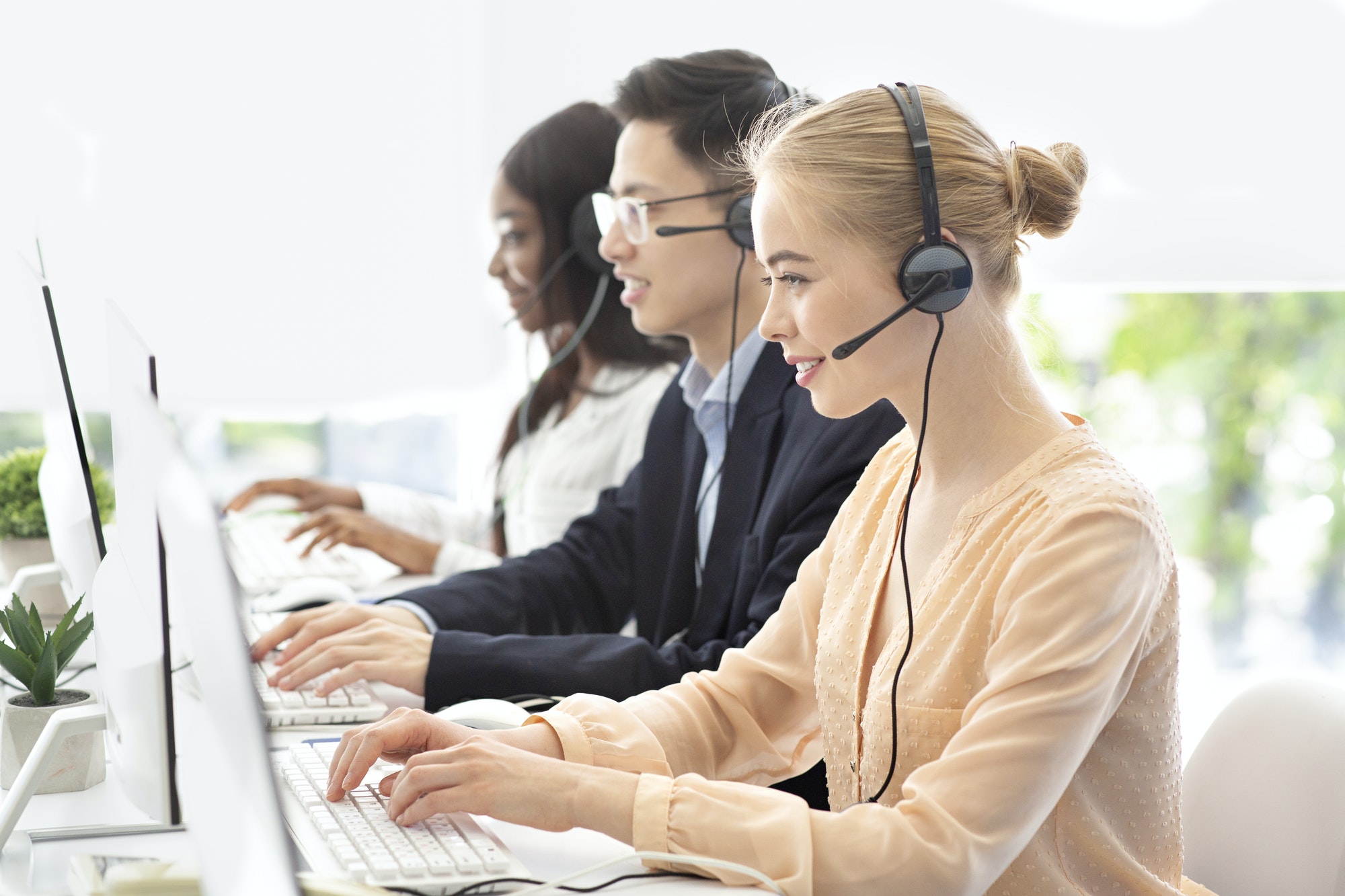 Team of hotline operators with headsets communicating to clients at modern call center, free space