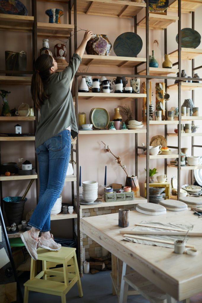 Woman Storing Ceramics on Shelf