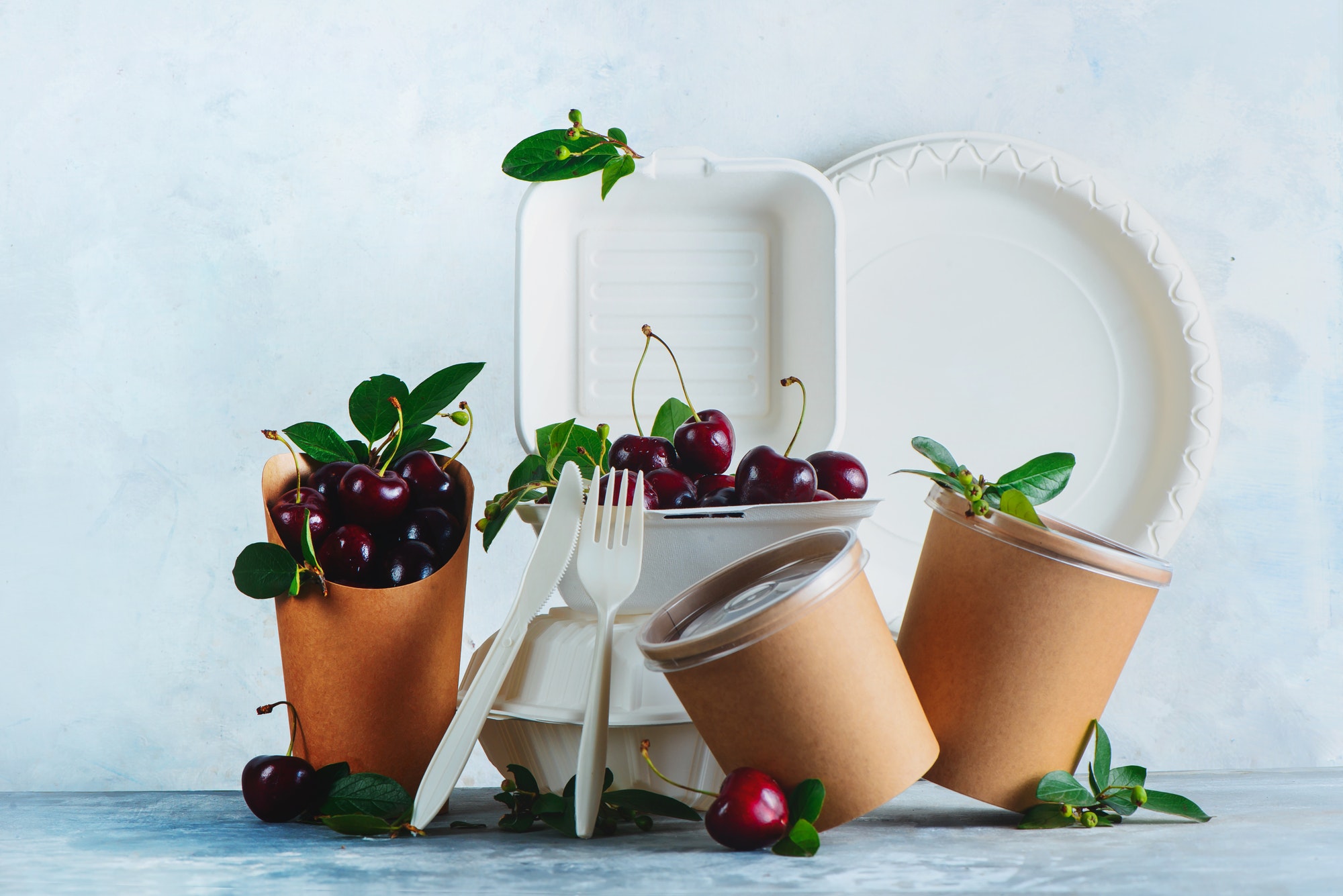 Catering disposables, cups, plates and containers with cherries. Eco-friendly food packaging on a
