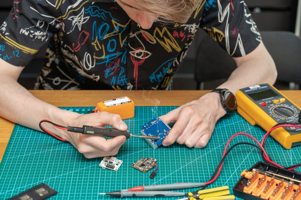 Technician engineer in workshop. Repairman is soldering circuit board of electronic device