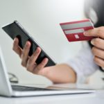 Young woman holding credit card and smartphone with laptop, Credit card payment.