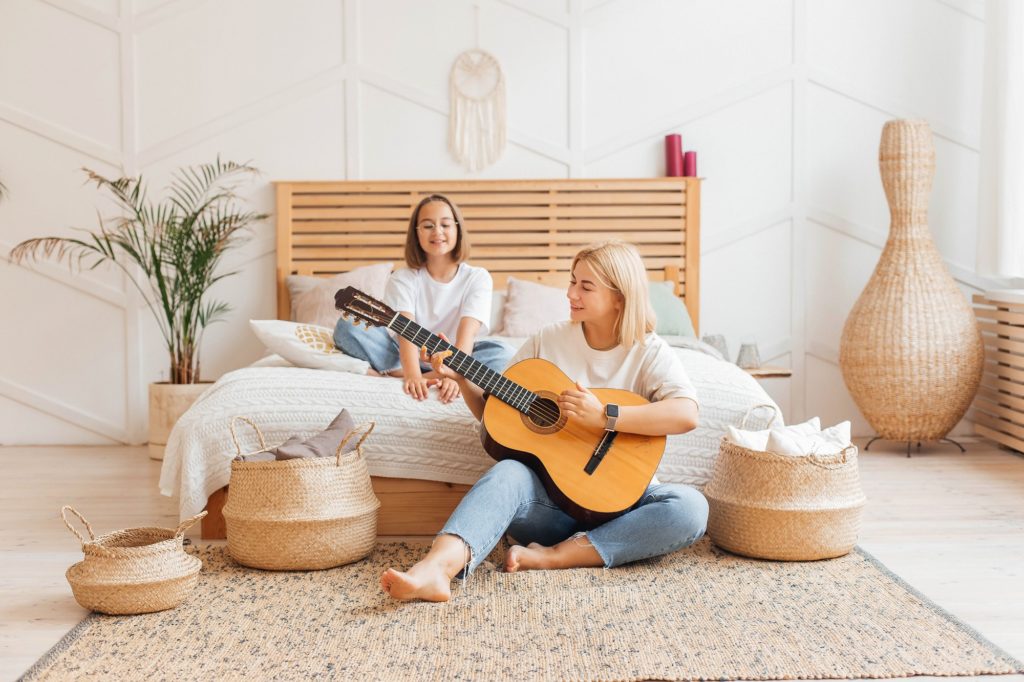 Mother plays the guitar to her daughter, happy family