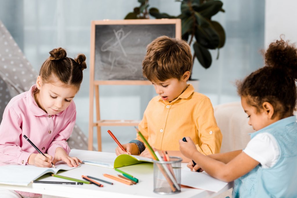 adorable little multiethnic kids drawing and studying together