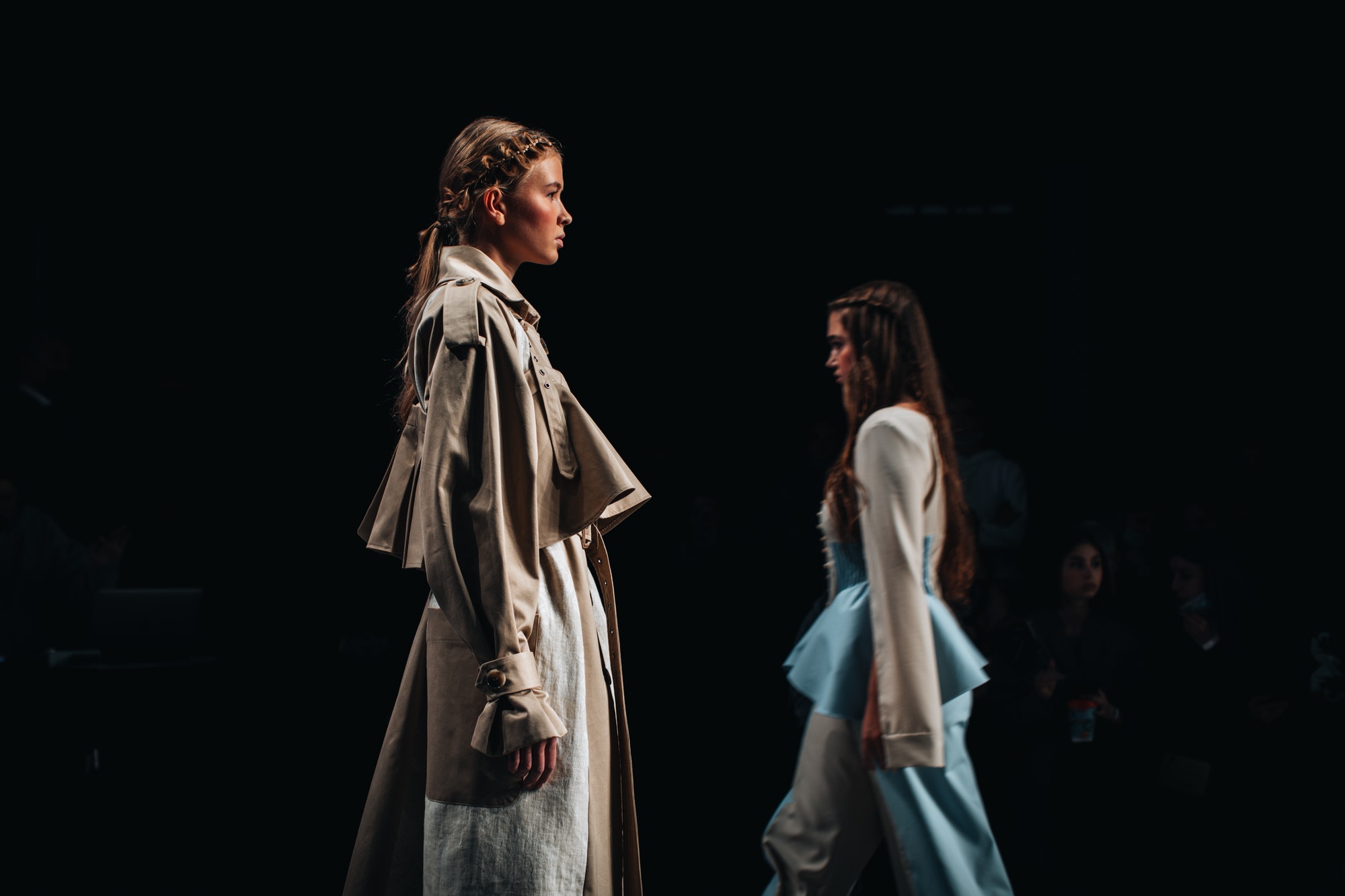Two fashion models on the catwalk on a black background. Autumn collection at Fashion Week