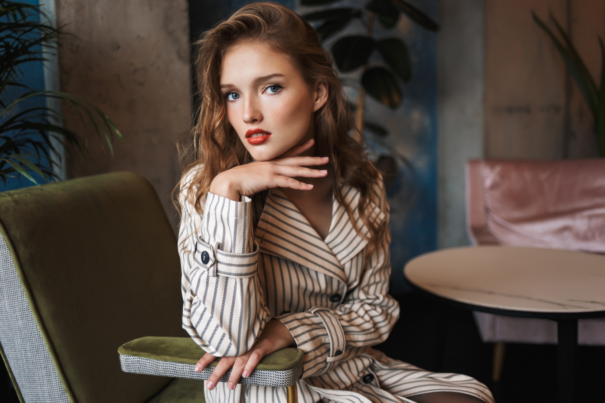 Young beautiful woman with wavy hair in striped trench coat lean