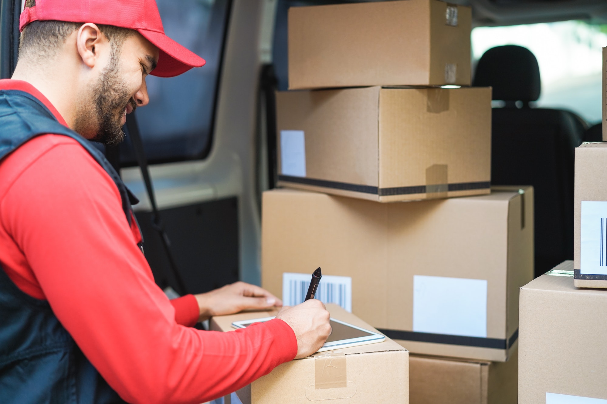 Happy courier man signing package delivery in van truck - Focus on face
