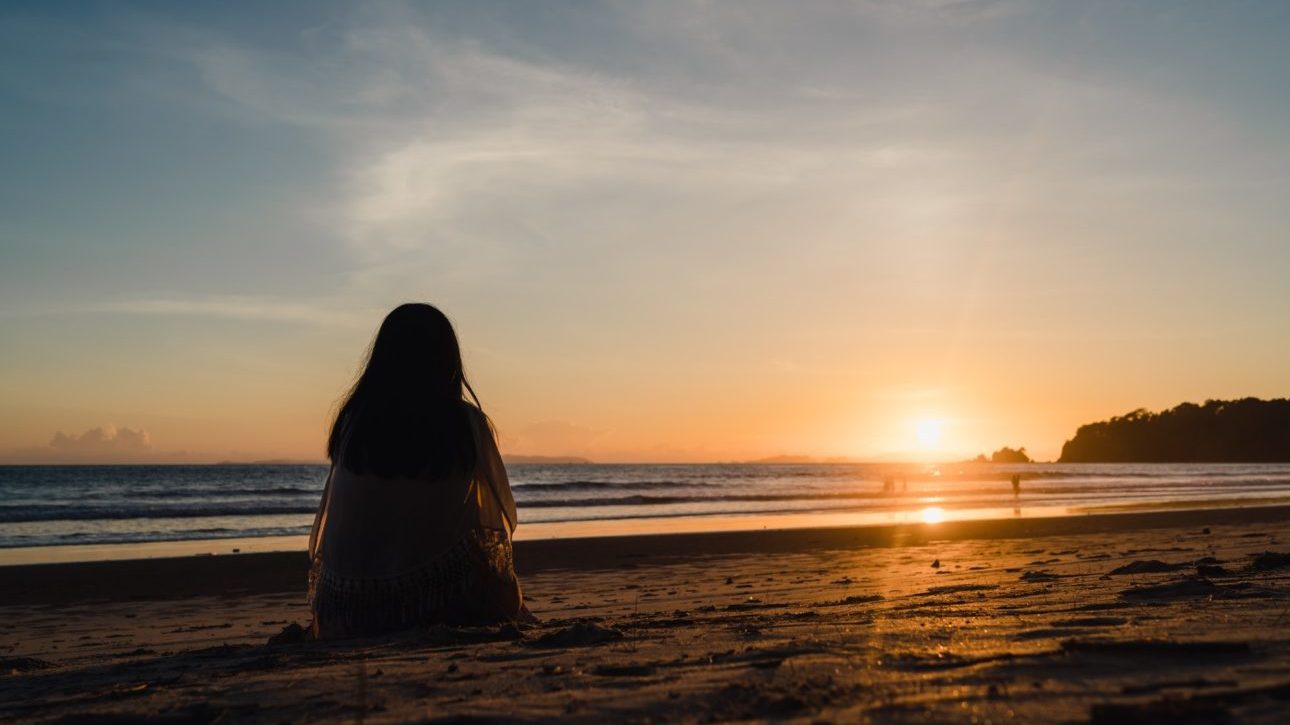 Young Asian woman watching sunset near beach.