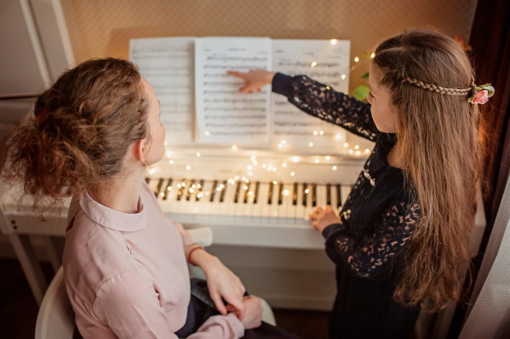 Woman and girl doing a music lesson on piano sheet music