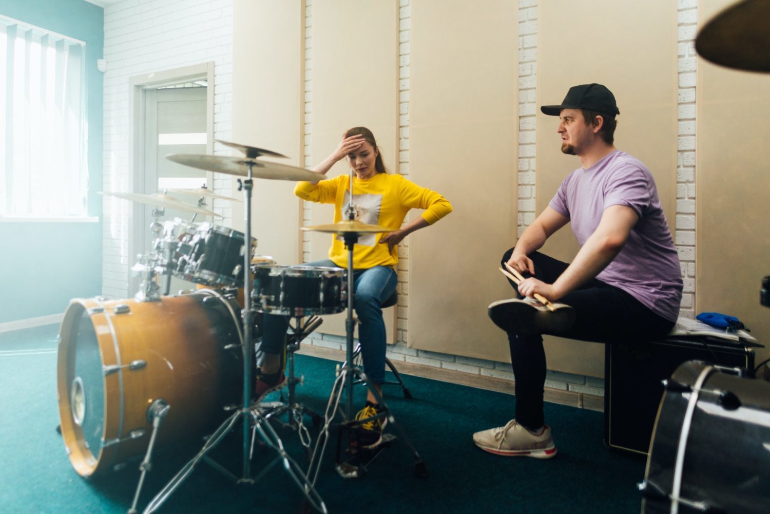 Young woman learning to play drums with teacher.