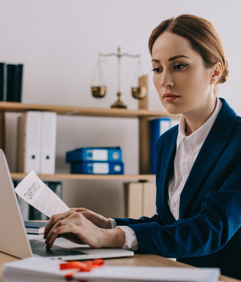 focused female lawyer working on laptop at workplace in office