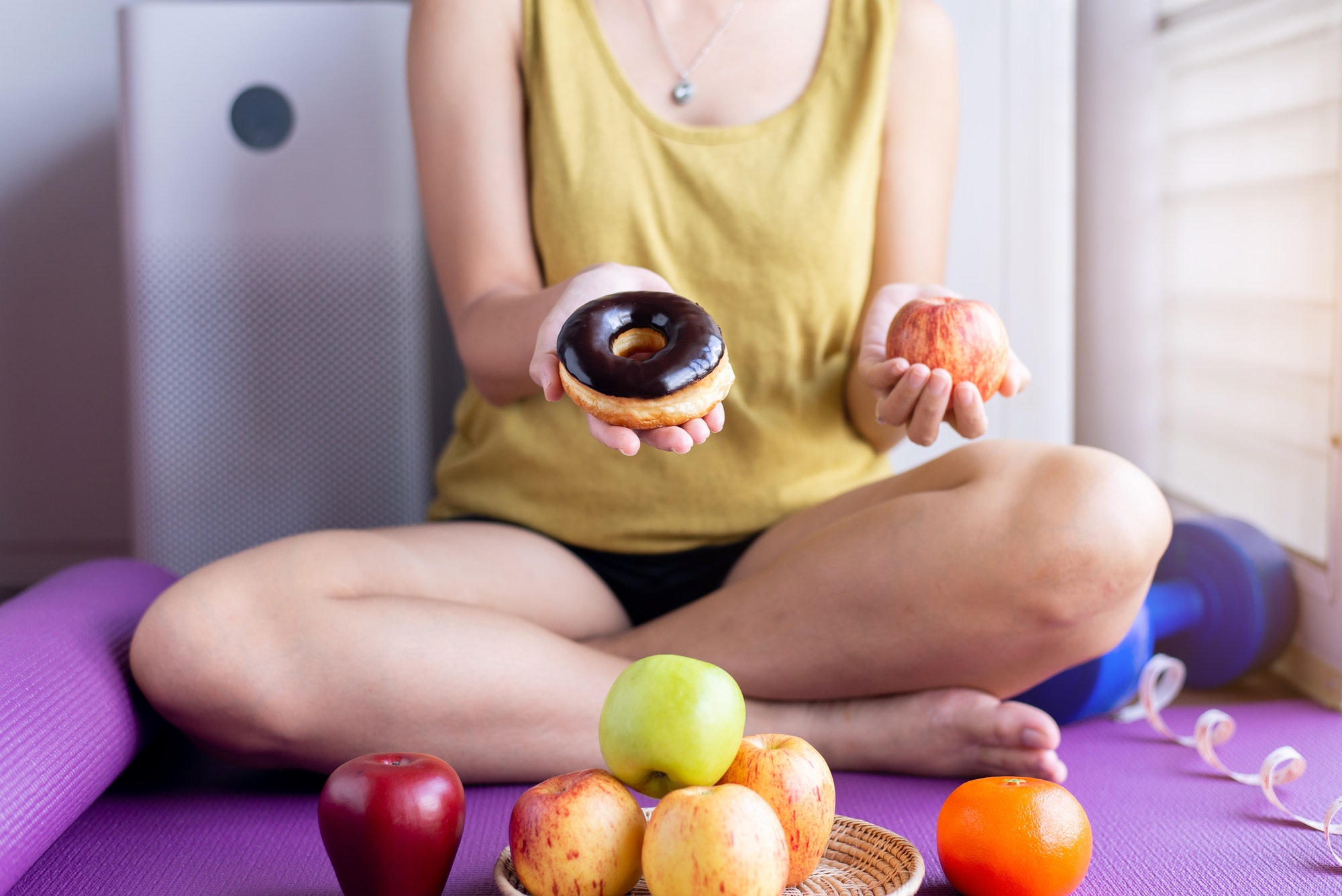 Woman hands holding red apple and baked chocolate donut at home,Healthy diet,Dieting concept