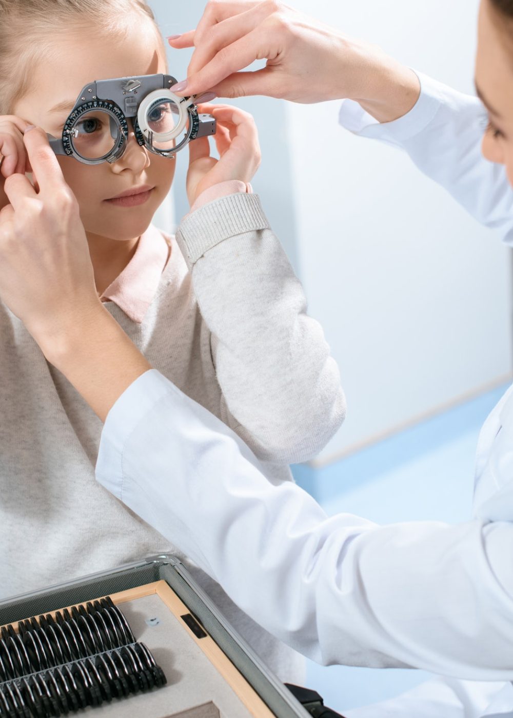 female ophthalmologist examining kid eyes with trial frame and lenses