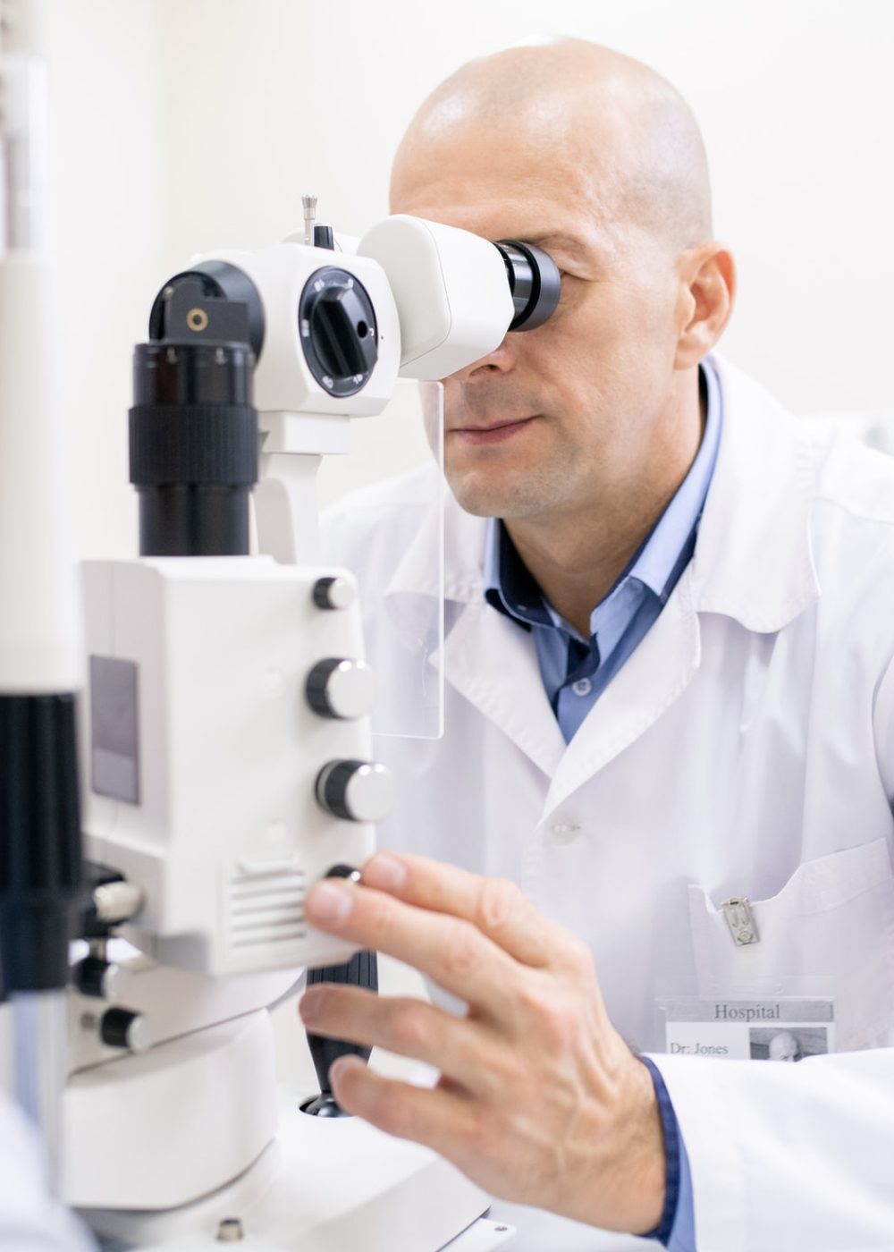 Middle aged professional optometrist checking eyesight of female patient