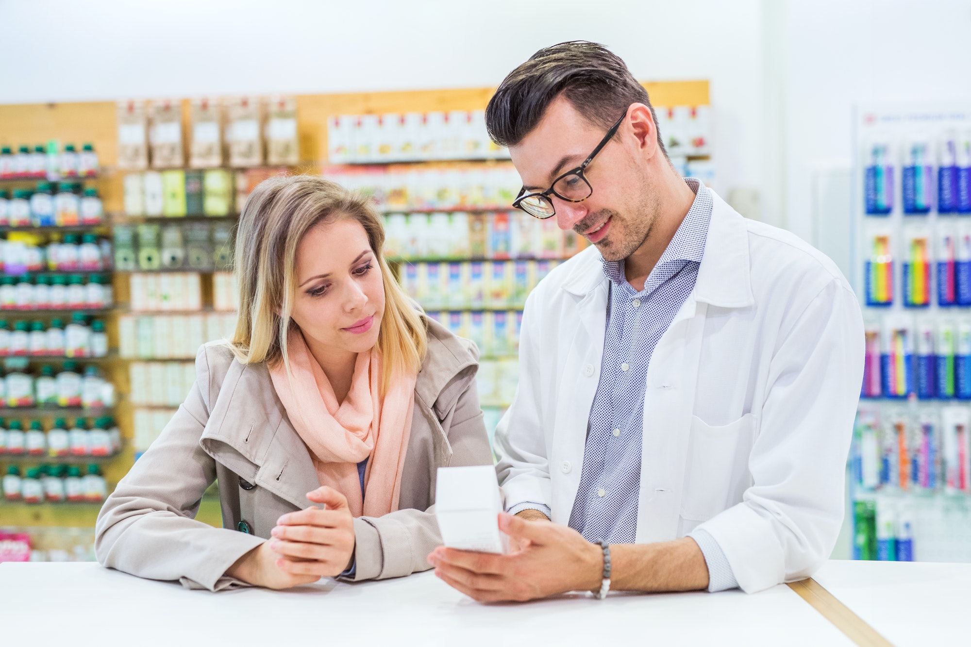 Male pharmacist serving a female customer.