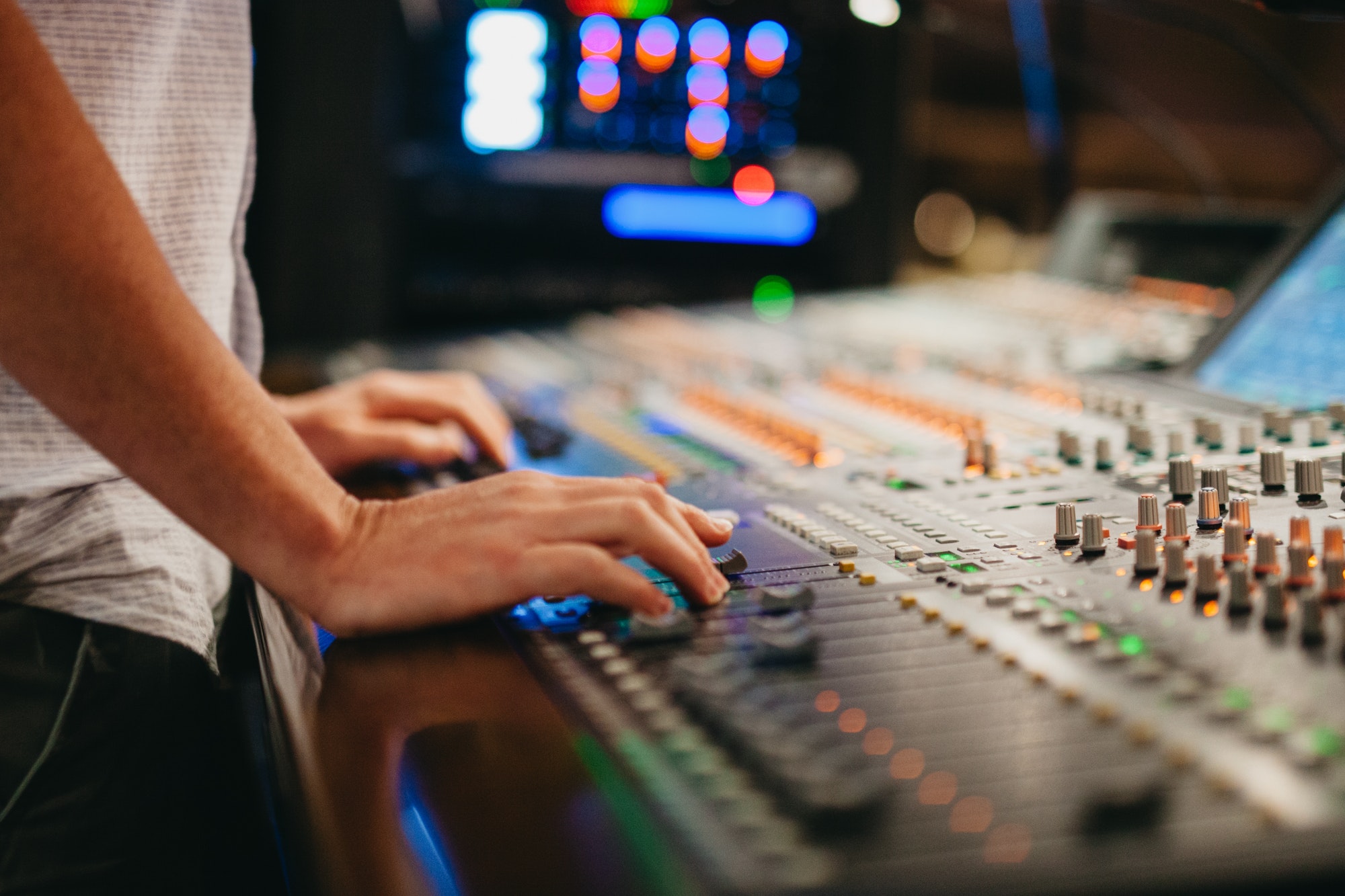 A sound tech works on a mixing board changing levels of the music production.