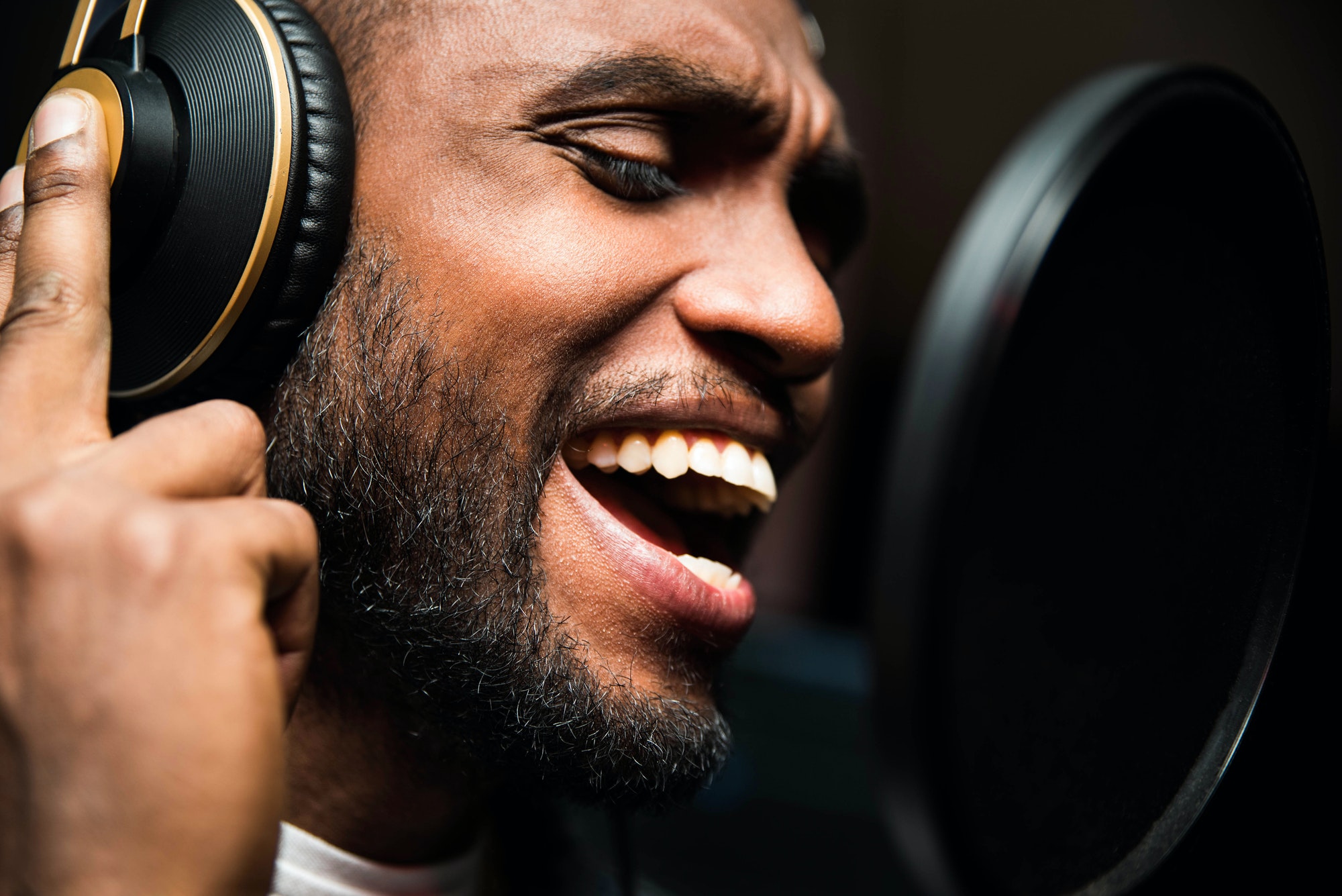 Bearded afro american man singing to microphone recording song in music studio production