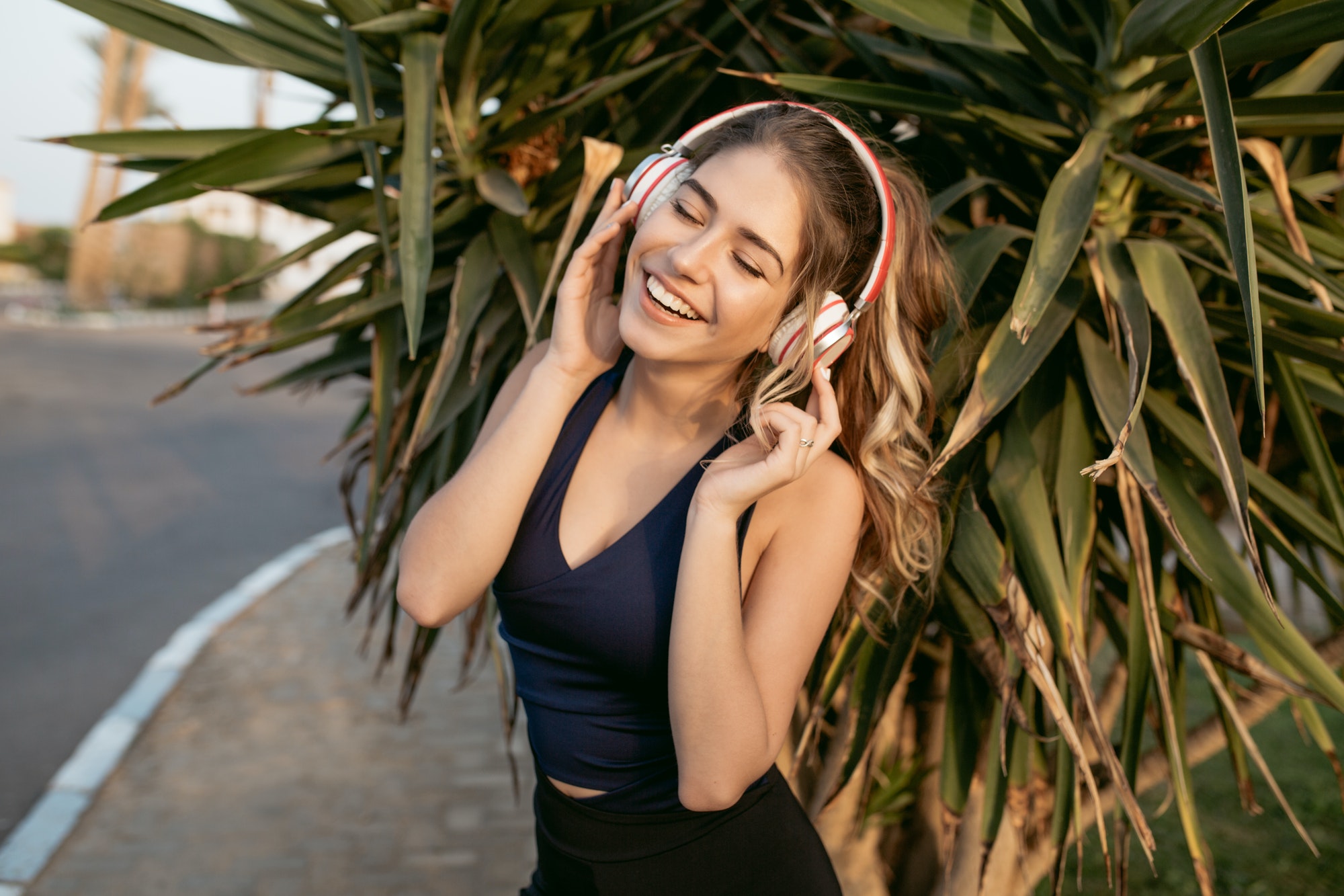 Portrait happy sunny morning of sportive young woman smiling with closed eyes, hearing music through