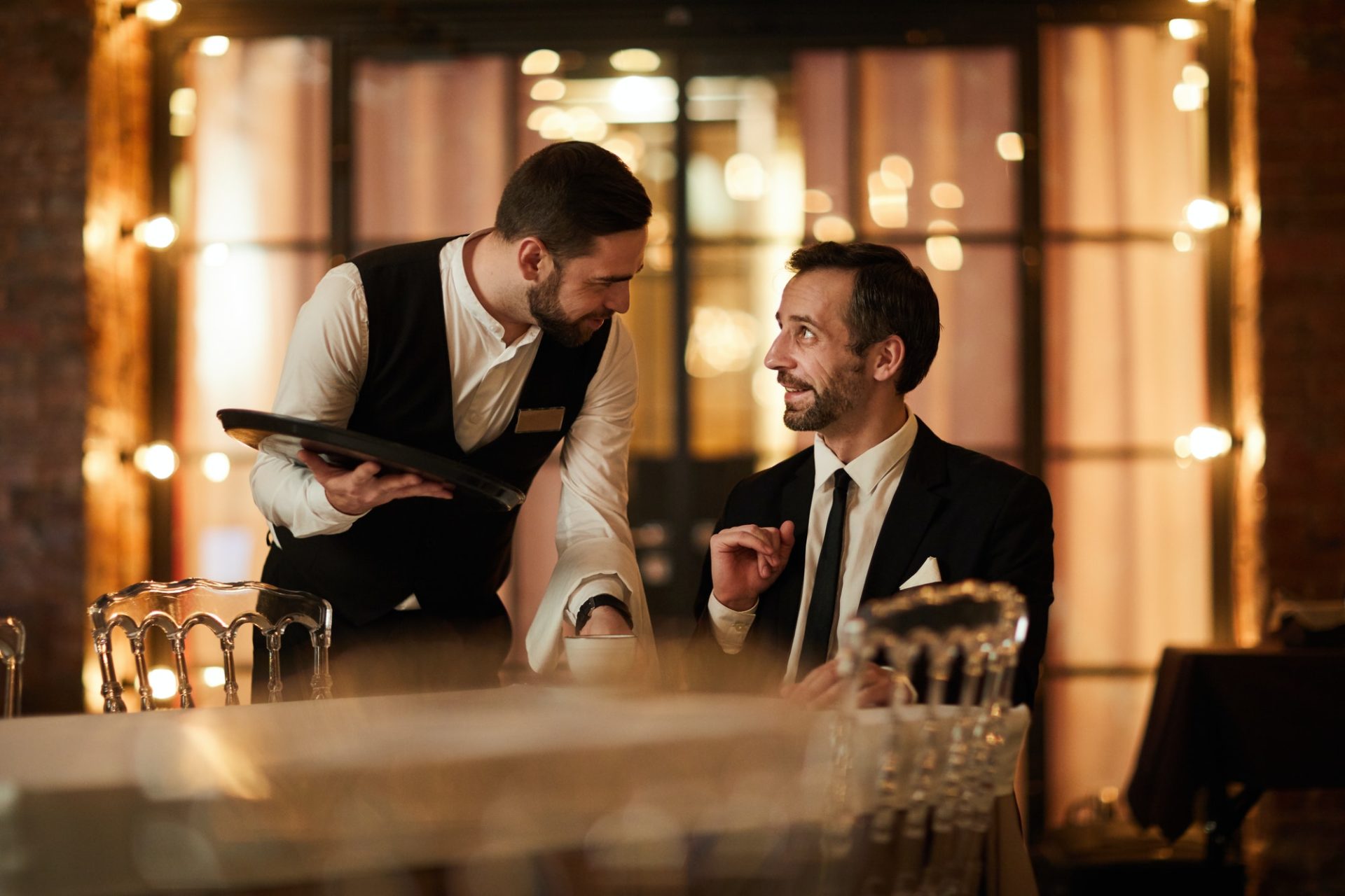 Smiling Businessman Talking to Waiter in Restaurant