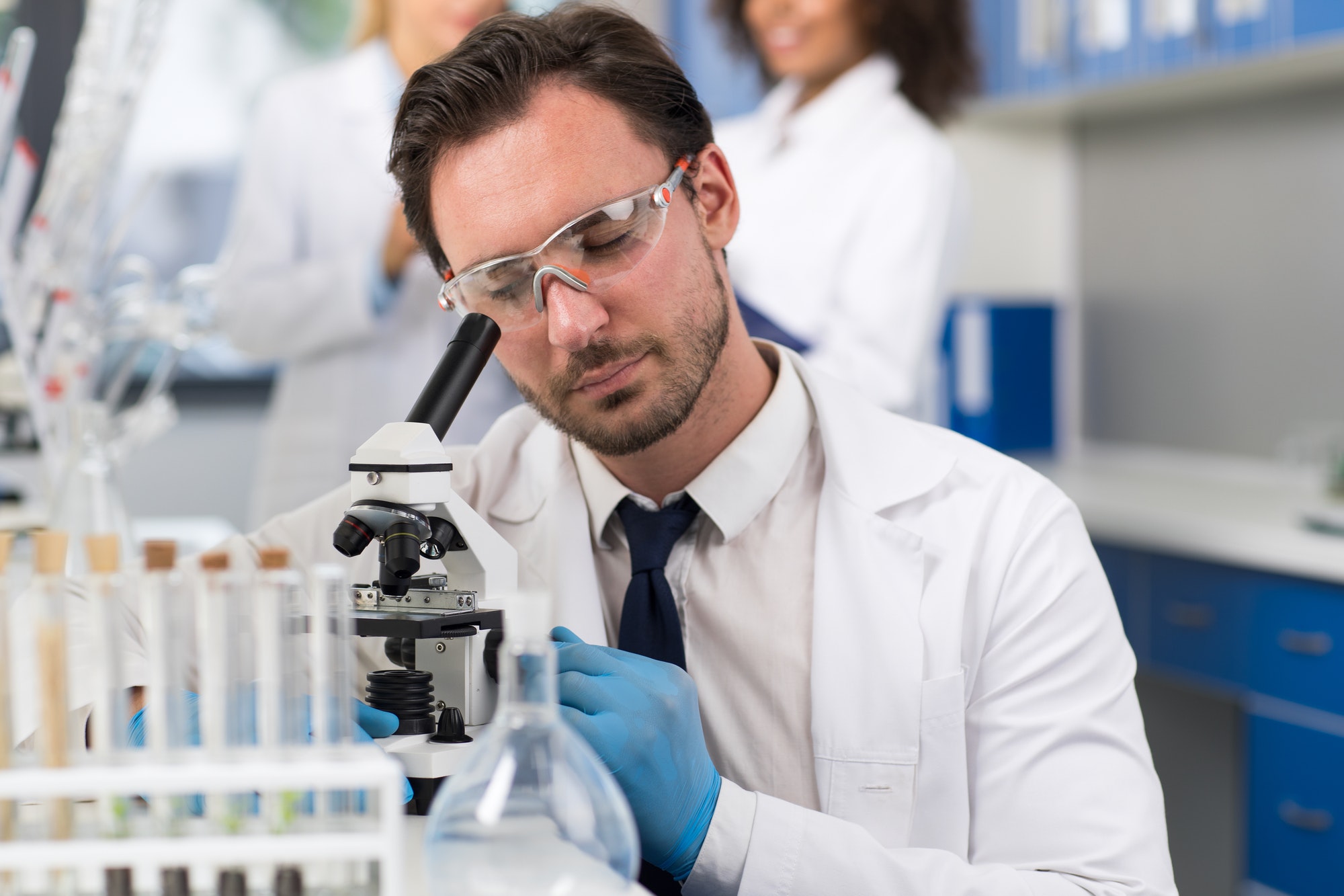 Scientist Looking Through Microscope In Laboratory, Male Researcher Doing Research Experiments