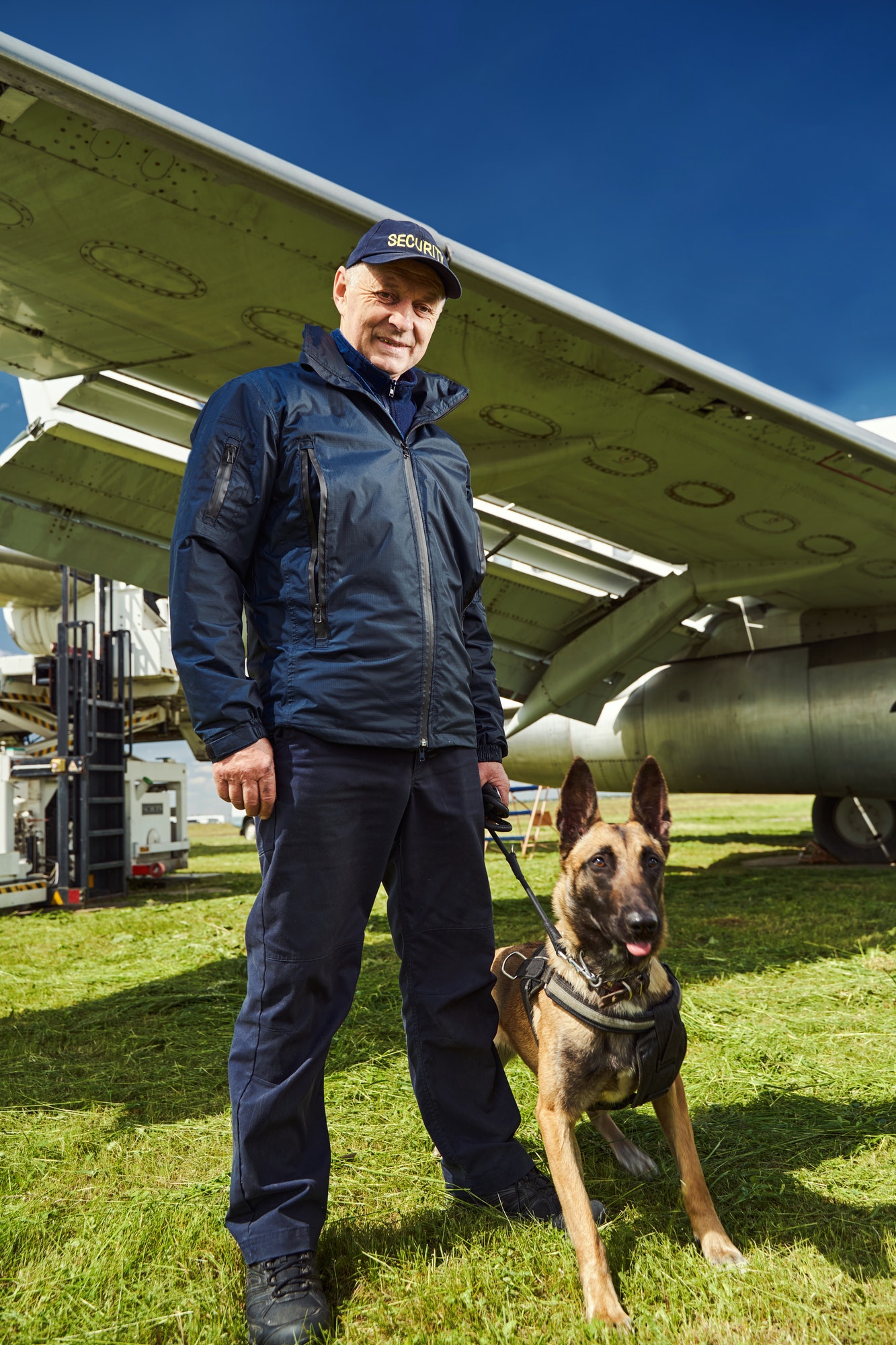 Security officer with dog standing near plane at aerodrome