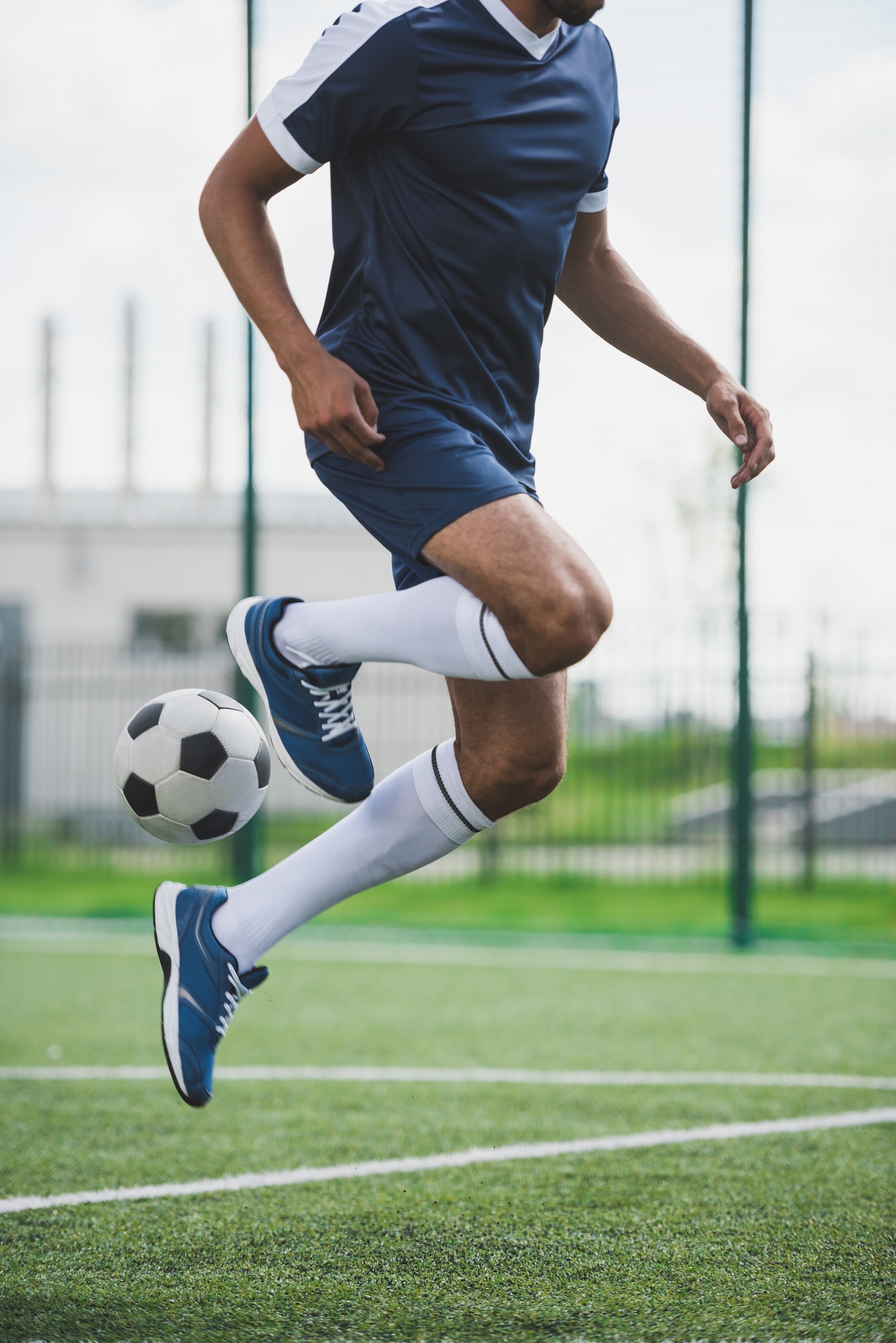 cropped shot of athletic soccer player training with ball on soccer pitch