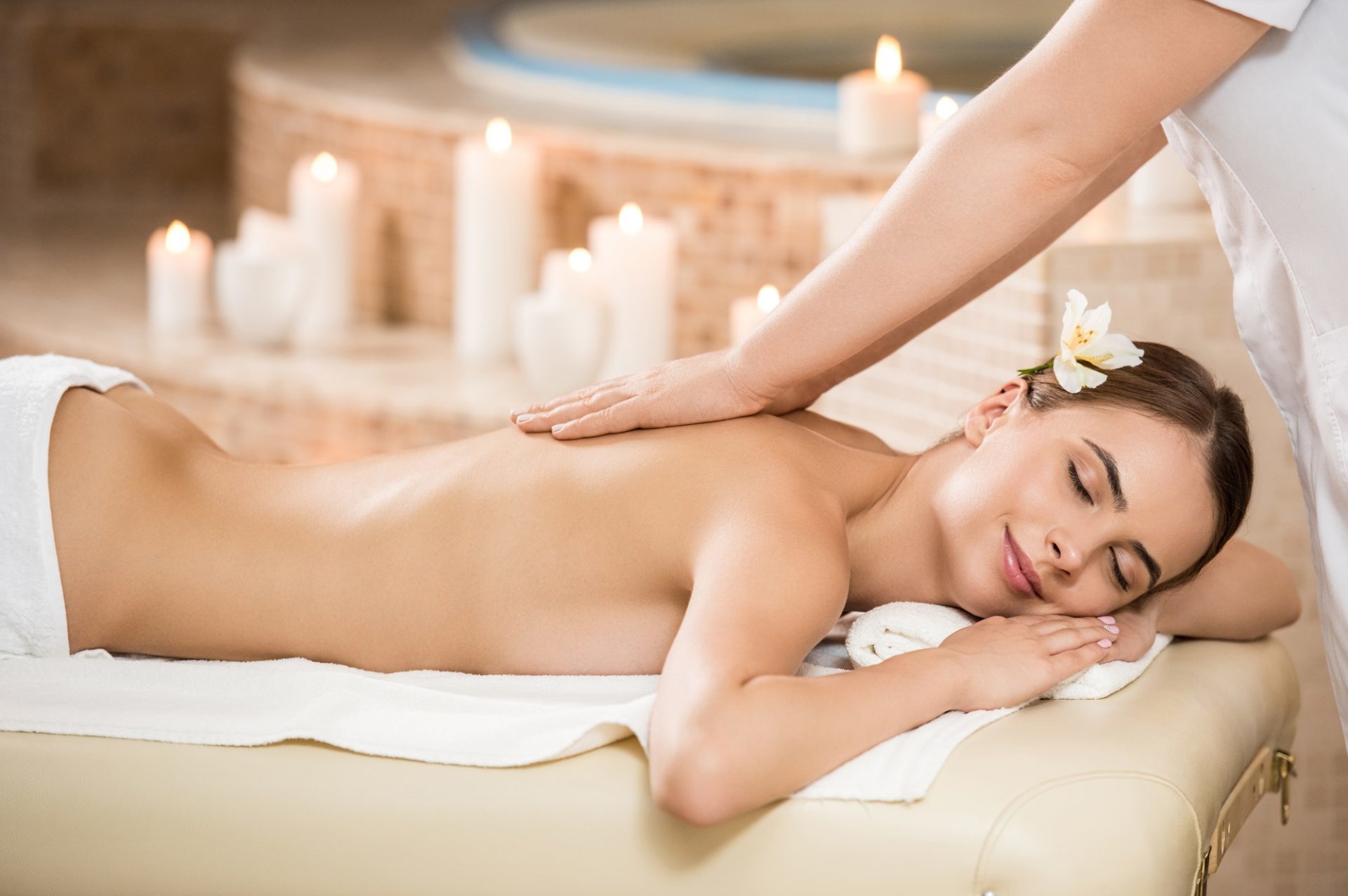 massage therapist making massage for gorgeous woman in spa salon