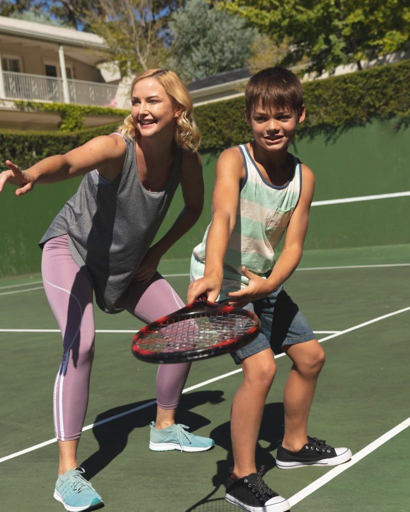 Caucasian mother and son outdoors, playing tennis on tennis court
