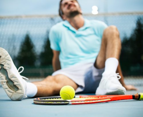 Tired tennis player man on tennis court with racket