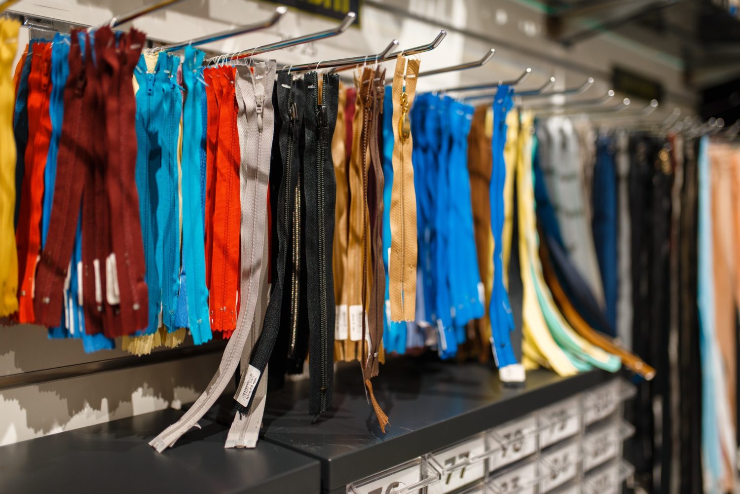Colorful zippers on shelf in textile store, nobody