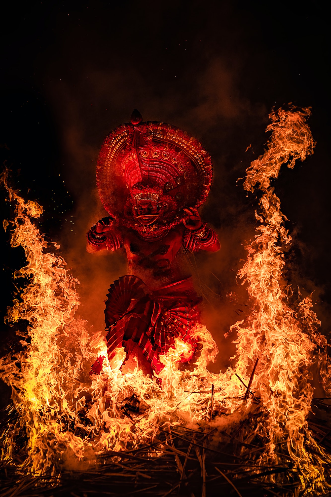 Man performing theyyam ritual form of dance worship surrounded b