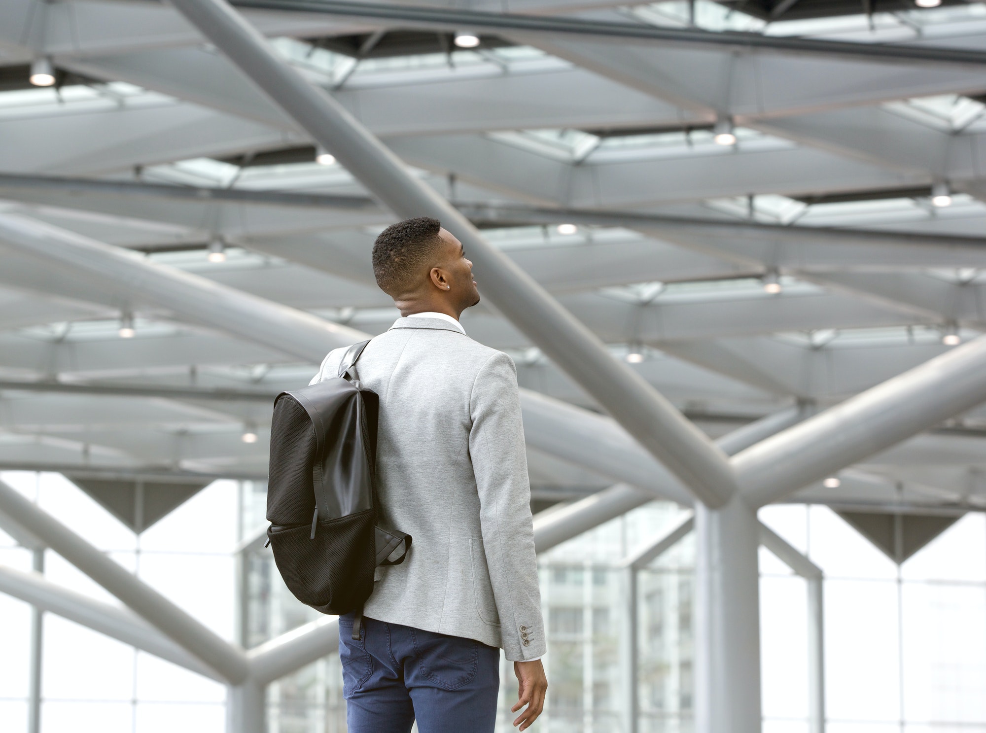 Black man standing alone in airport with bag