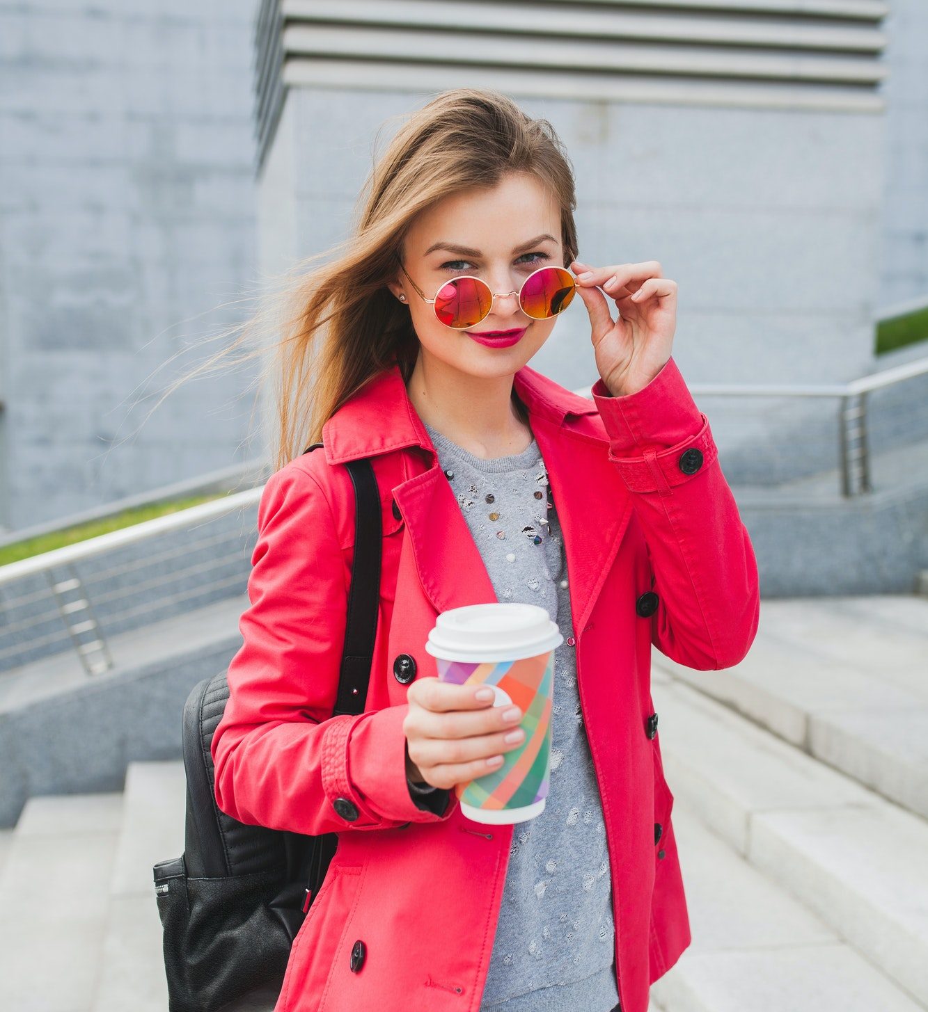 young hipster woman in pink coat, jeans in street